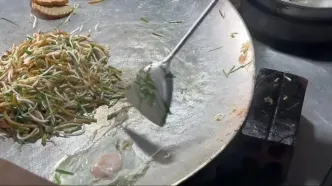 ببینید؛ غذای خیابانی در کامبوج؛ پخت رشته فرنگی سرخ شده با کیک پیازچه در سیِم ریپ